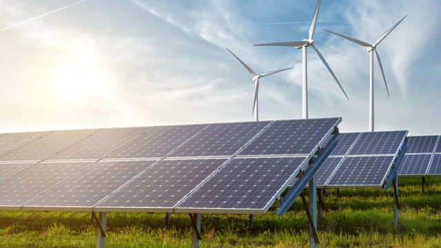 solar panels and wind generators under blue sky on sunset 