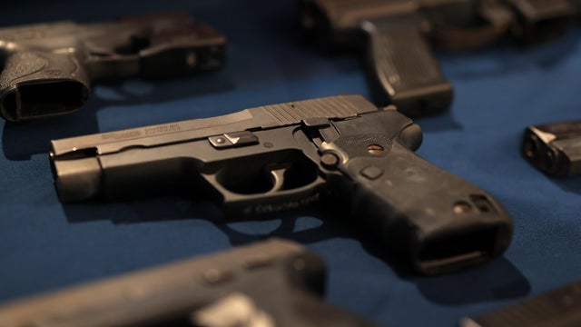 Confiscated guns are displayed on a table 